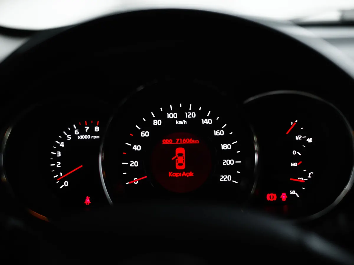 An instrument cluster glowing red in the dark, with warning lights lit beside the speedometer