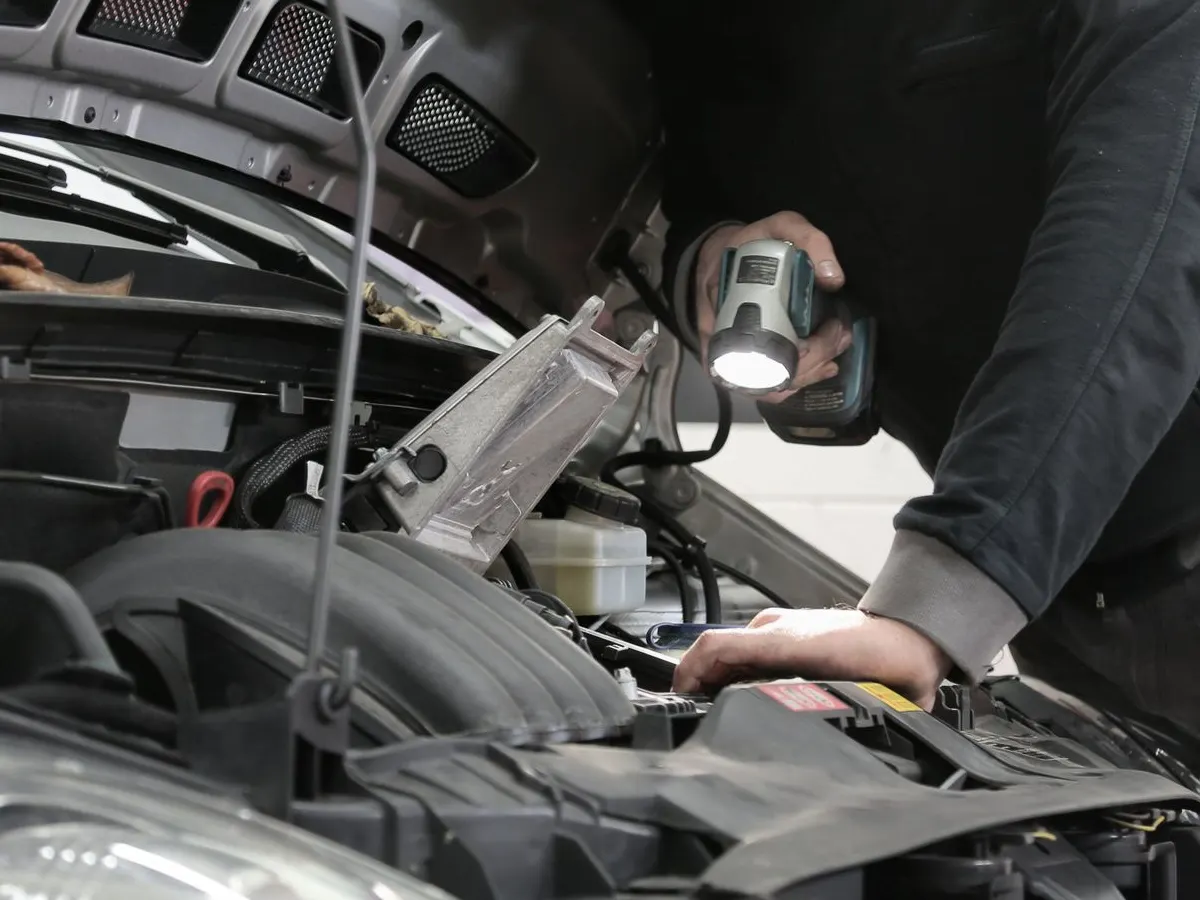 A technician's hands checking a component during a vehicle inspection