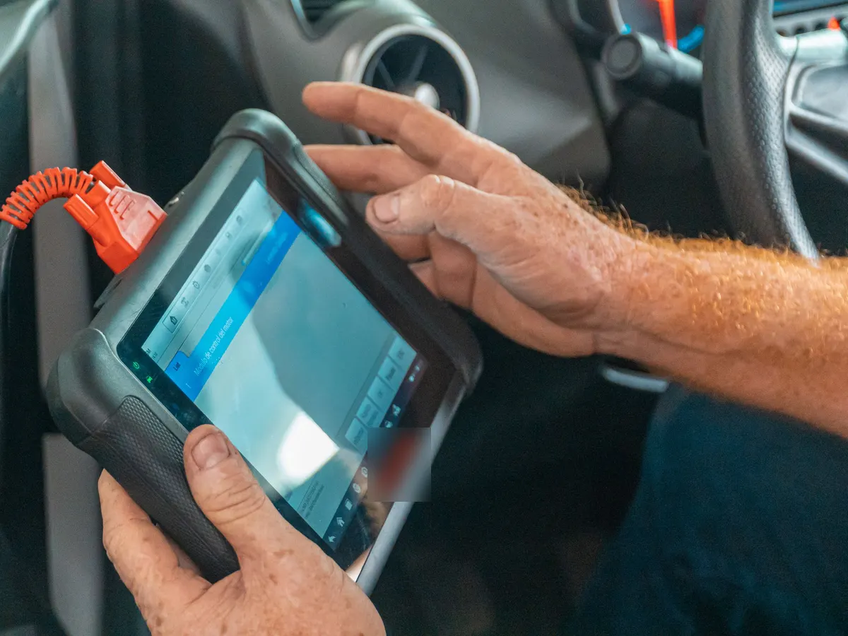 A technician reading live data from a car on a diagnostic tablet
